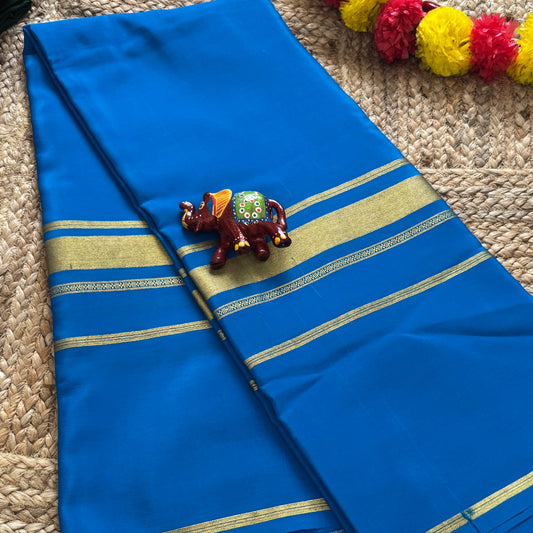 Blue saree with gold border on a textured surface with decorative items.